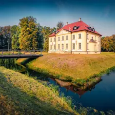 Pałac Branickich w Choroszczy, otoczony fosą i mostkiem, w blasku porannego słońca.