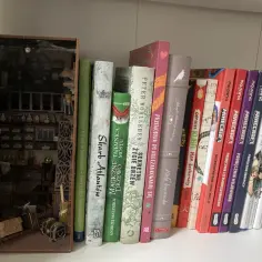 Miniaturowy book nook z detalami, jak z alchemicznej pracowni, obok kolorowych książek.