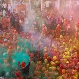 Tłum ludzi w kolorowym pyle podczas święta **holi**. Radosna atmosfera i eksplozja barw.