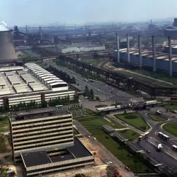 Widok na Huta Katowice, symbol przemysłu Śląska. Dymiące kominy i rozległe zabudowania budzą obawy o zatrucie ołowiem Śląsk.